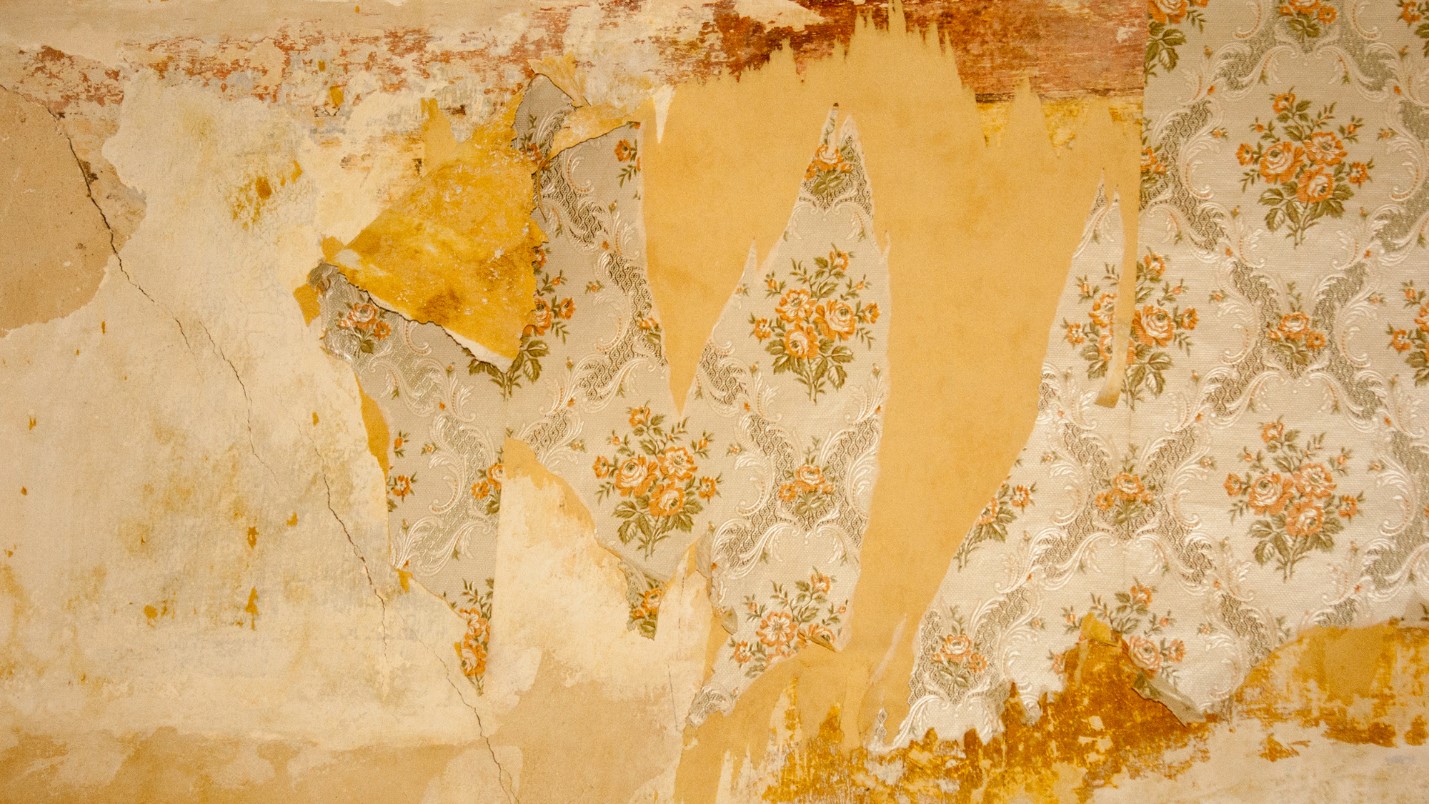 Old Faded Wallpaper That is Tattered in Places.