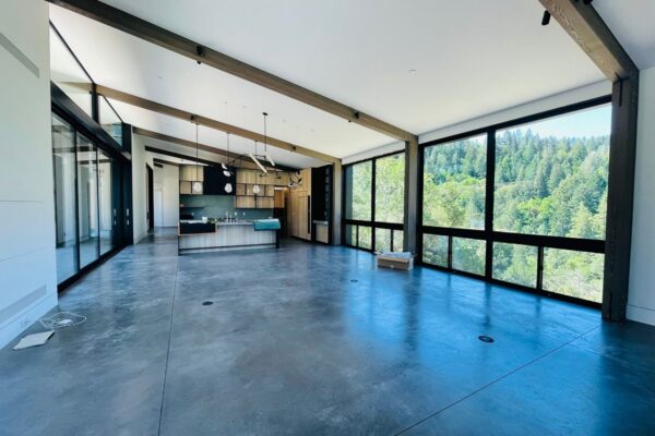 A sleek open-concept living room with white walls and dark beams.