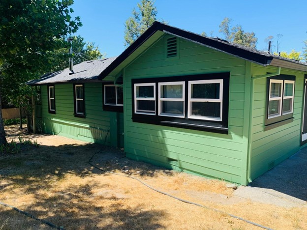 A home in the process of getting repainted, its blue paint is peeling off in patches.