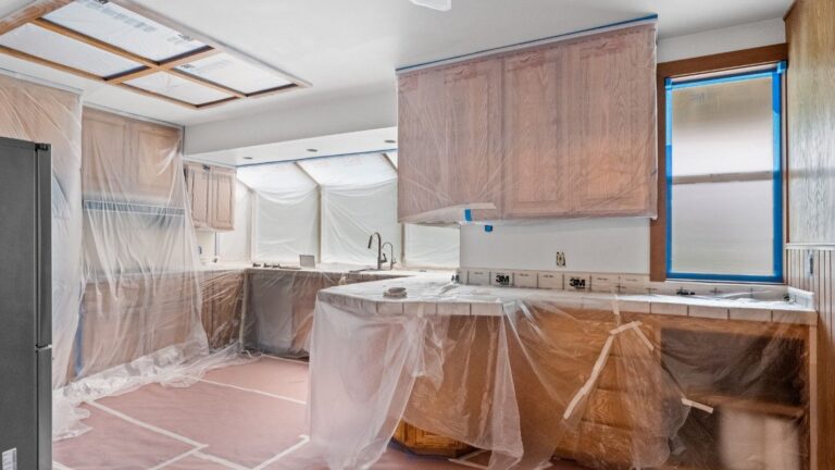 A kitchen covered in paper an plastic during a repainting