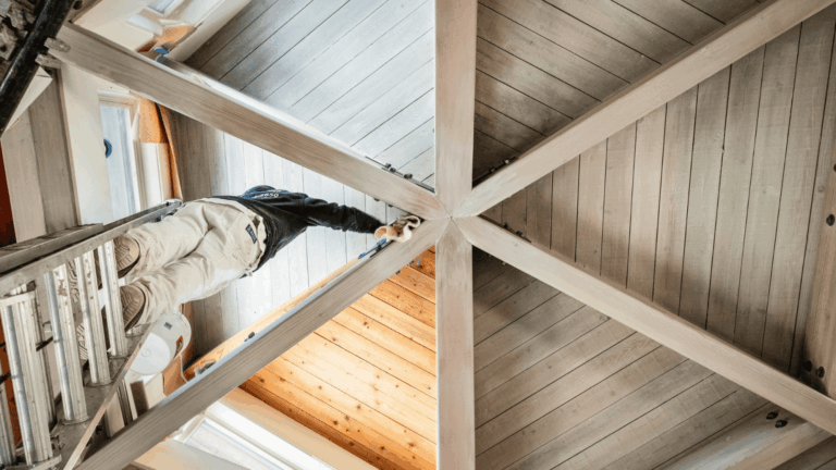 An intricate wooden ceiling being painted by professional painters
