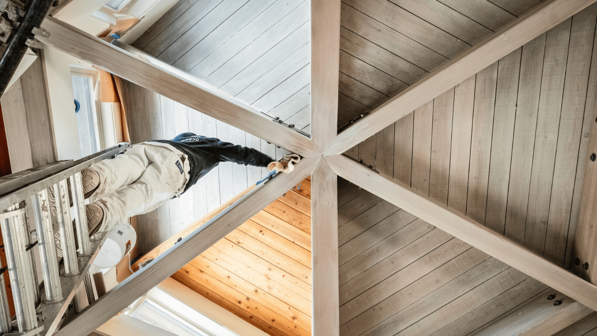 An intricate wooden ceiling being painted by professional painters
