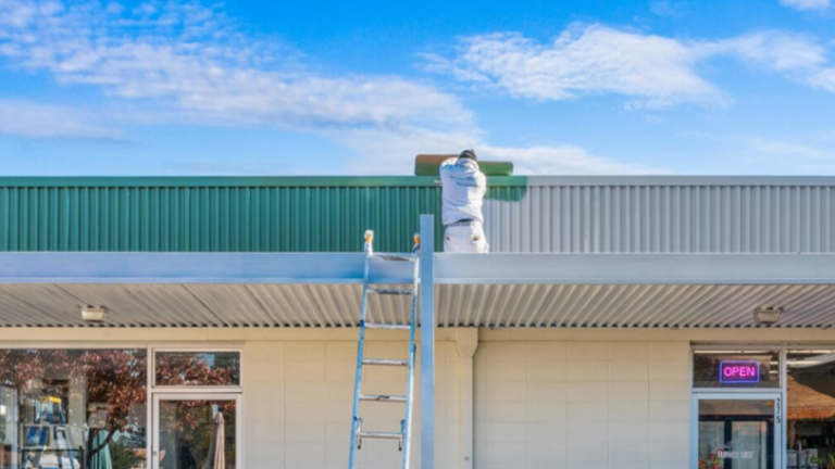 A painter working on a roof with one side painted green and the other unpainted