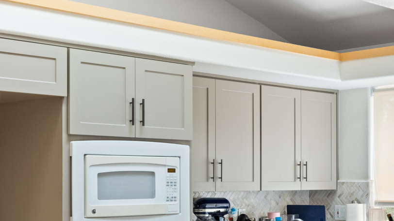 Kitchen cabinets that have been freshly painted in a light beige color.